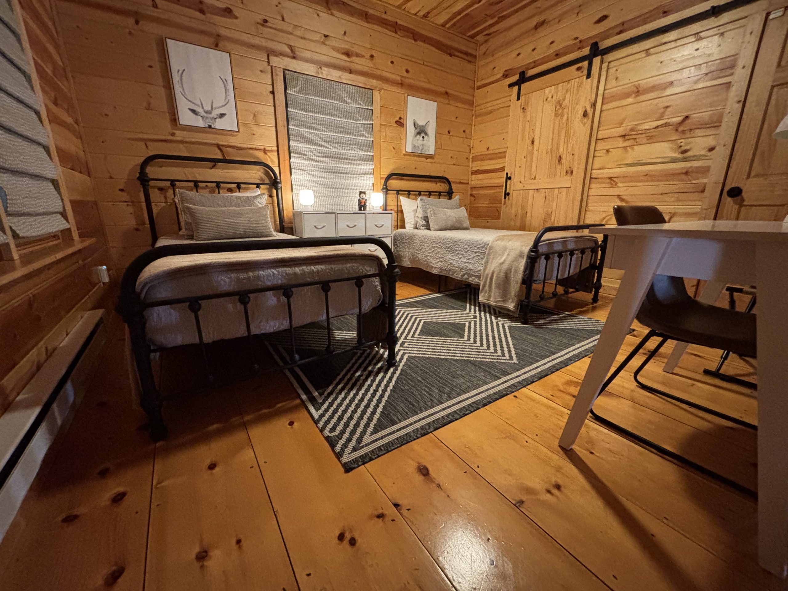 Updated open loft sleeping area with two twin beds and new bedside lamps at The Cozy Nook