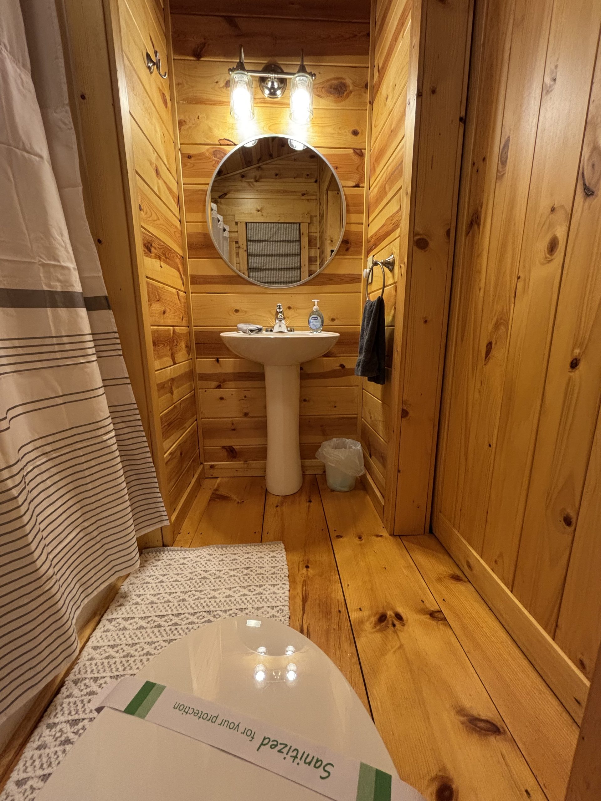 Second bathroom with pedestal sink and warm wood interior at The Cozy Nook cabin